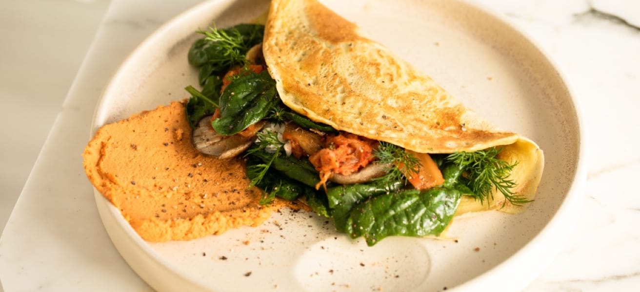 A freshly made simple omelette on a white plate sprinkled with green herbs